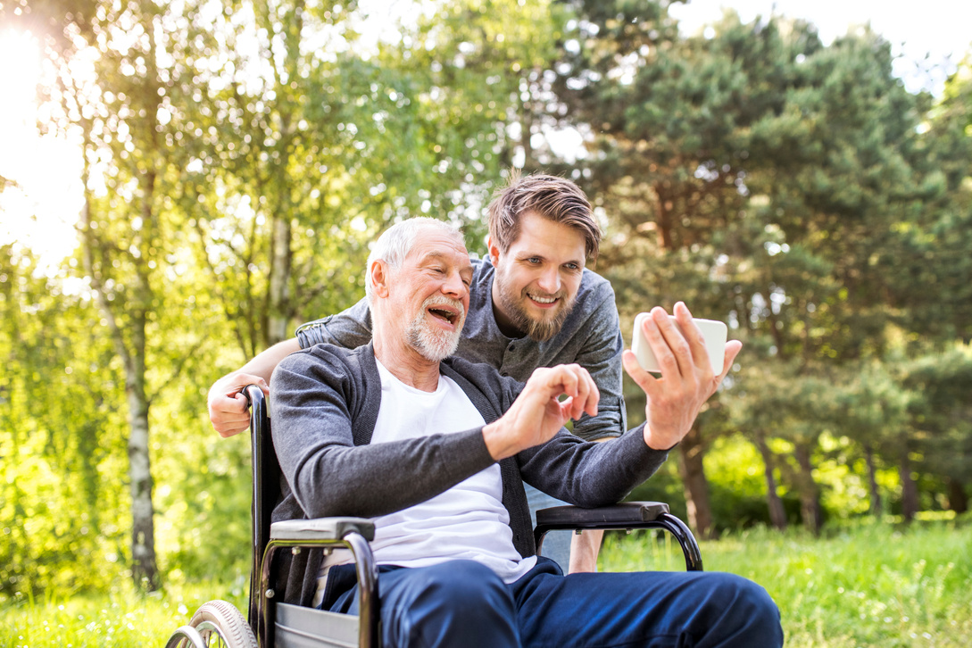 Hipster Son and Father in Wheelchair at Park Taking Selfie